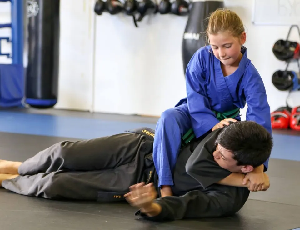 Child in blue martial arts uniform applies a technique on a partner during training at NEXUS Cairns.